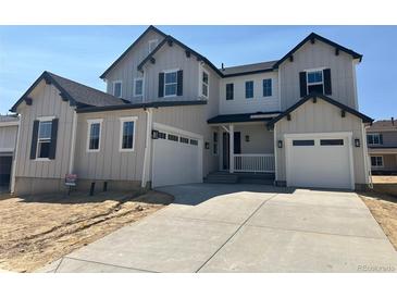 Charming two-story home with light-grey siding, black trim, an attached two-car garage, and an inviting front porch at 5500 Tamarack Ave, Firestone, CO 80504
