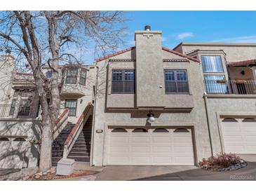 Charming townhome featuring a two-car garage and stucco siding, complete with a cozy front porch entrance at 1530 S Quebec Way # 34, Denver, CO 80231