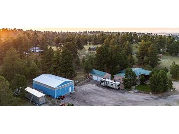 Spacious property with a large blue outbuilding, RV parking, and mature trees at 1059 S Elbert St, Elizabeth, CO 80107