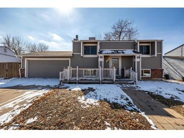 Two-story home with a well-manicured front yard, a wood porch, and attached garage at 15716 E Temple Pl, Aurora, CO 80015