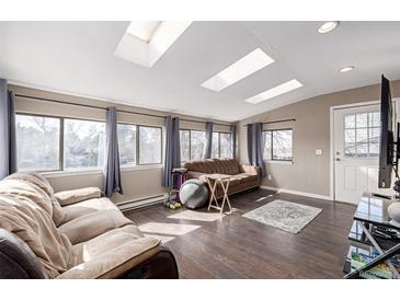 Bright living room featuring hardwood floors, skylights, and large windows with natural light at 15716 E Temple Pl, Aurora, CO 80015