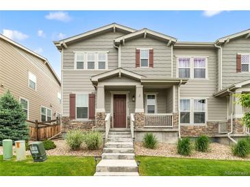 Charming two-story townhouse featuring a covered porch, stone accents, and landscaped front yard at 4343 S Nepal Ct, Centennial, CO 80015