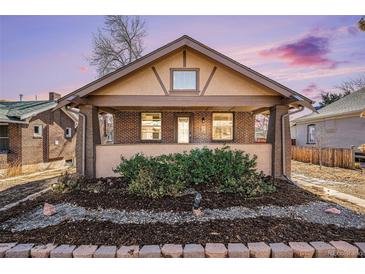 Charming brick home featuring a cozy front porch and well-manicured landscaping at 4440 W Hayward Pl, Denver, CO 80212