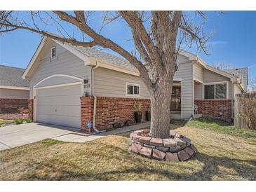 Charming home exterior featuring a well-maintained lawn and mature tree with brick accents around the house at 2275 S Kenton St, Aurora, CO 80014