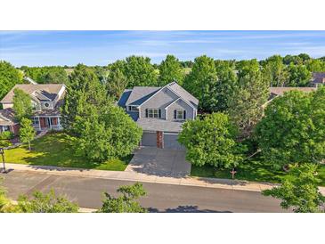 Charming two-story home featuring a manicured lawn, mature trees, and a welcoming gray exterior at 5746 Aspen Creek Dr, Broomfield, CO 80020