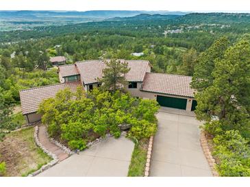 Expansive home with a red tile roof, nestled among trees with mountain views at 857 Pawnee Trl, Castle Rock, CO 80108