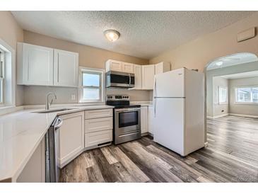 Bright kitchen features stainless steel appliances, white cabinetry, and gray wood-look flooring at 1746 Galena St, Aurora, CO 80010