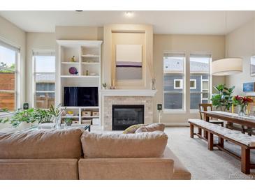 Bright living room featuring a fireplace, built-in shelving, and large windows with natural light at 9580 E 5Th Ave, Denver, CO 80230