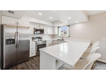 Bright kitchen with white cabinetry, stainless steel appliances, and a peninsula with seating at 3964 S Yosemite St, Denver, CO 80237