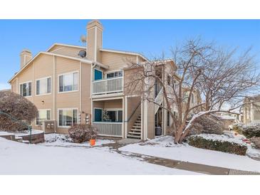Charming two-story townhouse with tan siding and a cozy balcony, surrounded by a snowy landscape at 3847 Mossy Rock Dr # 104, Highlands Ranch, CO 80126