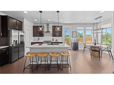 Bright eat-in kitchen featuring a spacious island with barstool seating and modern stainless steel appliances at 6700 Clay St, Denver, CO 80221