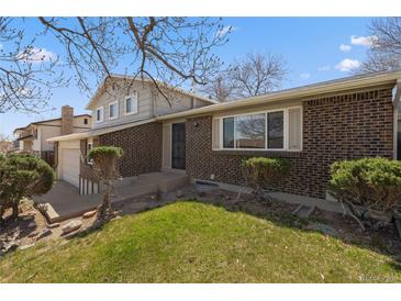 Charming brick home featuring a well-maintained lawn and mature landscaping at 7181 Beech St, Arvada, CO 80004