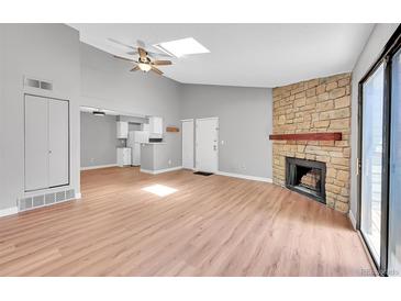 Inviting living room with vaulted ceilings, skylight, wood floors, stone fireplace, and sliding door to the outside at 12023 E Harvard Ave # 203, Aurora, CO 80014