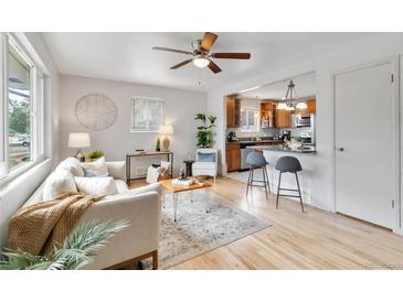 Bright living room featuring hardwood floors, ceiling fan, and open layout to the kitchen at 11433 Carlile St, Northglenn, CO 80233
