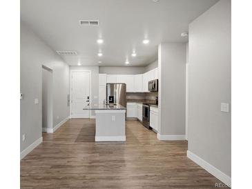 A modern kitchen featuring stainless steel appliances, white cabinets, and a granite countertop island at 981 S Sable Blvd # 107, Aurora, CO 80012