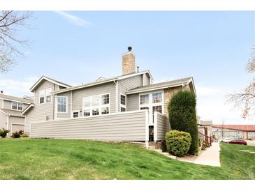 An exterior view of the home showing a two-story home with gray siding and a stone chimney at 6858 Zenobia St # 9, Westminster, CO 80030
