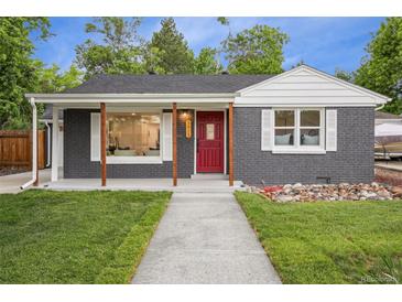 Charming single-story home with gray brick, a red door, and a well-manicured lawn at 5515 Dudley Ct, Arvada, CO 80002