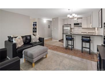 Open-concept living area featuring a modern kitchen with stainless steel appliances and black countertops at 7040 E Girard Ave # 310, Denver, CO 80224