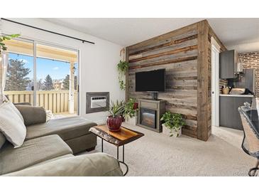 Inviting living room featuring a decorative fireplace, reclaimed wood wall, and access to the outdoor balcony at 3035 Oneal Pkwy # 36T, Boulder, CO 80301