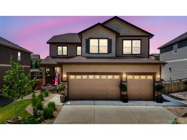 Charming two-story home featuring a three-car garage and landscaped front yard at dusk at 7514 Blue Water Dr, Castle Rock, CO 80108