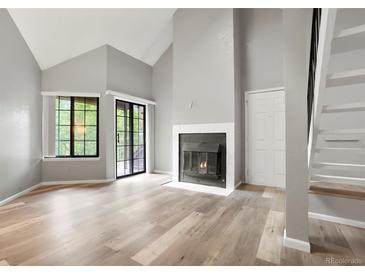 Bright living room features a fireplace, sliding glass door, modern flooring, and soaring vaulted ceilings at 832 S Vance St # F, Lakewood, CO 80226