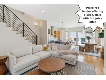 Bright, open living room flows to kitchen and dining area featuring modern staircase and hardwood floors at 2244 S Lincoln St, Denver, CO 80210