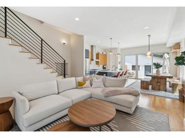 Bright living room featuring an L-shaped couch, modern staircase, and open floor plan flowing into the kitchen and dining area at 2244 S Lincoln St, Denver, CO 80210