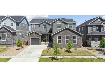 Charming two-story home featuring stone accents, a well-manicured lawn, and a welcoming facade at 671 Green Mountain Dr, Erie, CO 80516