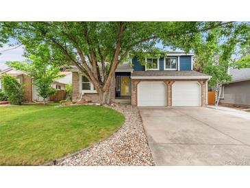 Charming two-story home with a manicured lawn, brick accents, and a two-car garage at 7035 S Flower Ct, Littleton, CO 80128