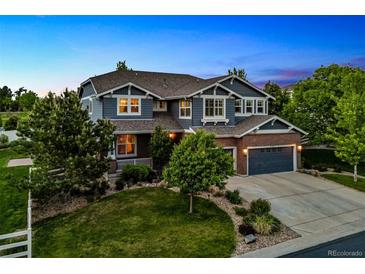 Beautiful two-story home with a well-manicured lawn and mature trees at dusk at 16267 W 59Th Pl, Golden, CO 80403