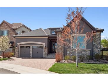 Charming gray home featuring a stone accent wall, a tiled roof, and a brick paver driveway at 6970 E Lake Dr, Centennial, CO 80111
