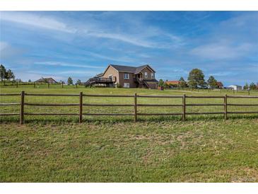 Two-story home featuring a deck, visible through a wooden fence, surrounded by a lush green lawn at 2501 Remington Rd, Elizabeth, CO 80107
