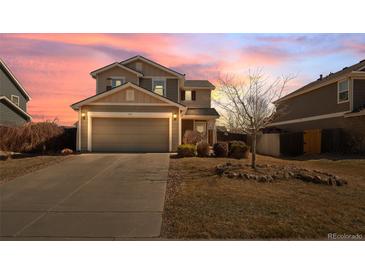 Two-story home with neutral siding, an attached garage, and a well-maintained front yard at sunset at 896 Willow Dr, Brighton, CO 80603