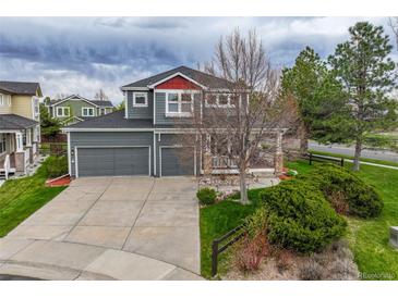 Inviting two-story home featuring a well-manicured lawn, gray siding, a spacious porch, and an attached two-car garage at 16453 Homestead Ct, Parker, CO 80134