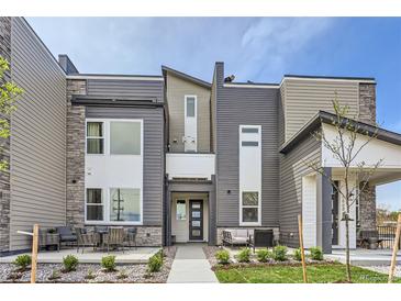Modern townhome with a landscaped front yard and a gray and white facade with outdoor seating at 2475 W 69Th Pl, Denver, CO 80221