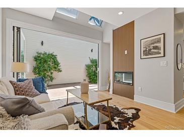 Bright living room featuring skylights, a fireplace, modern decor, and seamless indoor-outdoor flow to the patio at 434 Clayton St, Denver, CO 80206