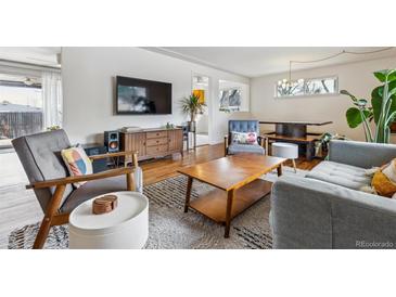 Open-concept living area with stylish furniture, hardwood floors, and a view to the dining area at 2738 S Newton St, Denver, CO 80236