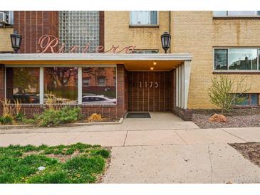 Condo building entrance with a brick facade and a vintage 'Riviera' neon sign, enhancing its classic curb appeal at 1175 N Emerson St # 103, Denver, CO 80218
