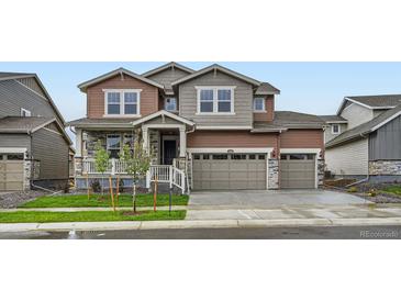 Two-story home with mixed siding, stone accents, three-car garage, and a well-maintained front yard at 4592 Windmill Dr, Brighton, CO 80601