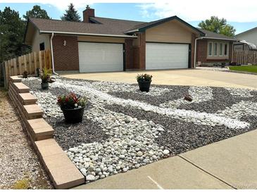 Charming home with a two-car garage and decorative rock landscaping featuring flower pots at 7784 Lewis St, Arvada, CO 80005