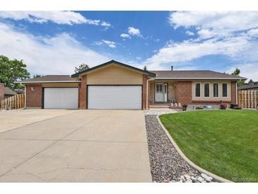 Charming single-story home with a brick facade, a well-manicured lawn, and an attached two-car garage at 7784 Lewis St, Arvada, CO 80005