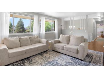 Bright living room featuring neutral furniture, large windows with sheer curtains, and stylish area rug at 2502 S Lima St, Aurora, CO 80014