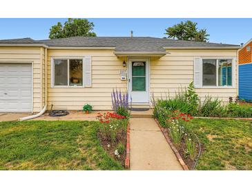 Charming yellow home with a well-manicured lawn and flower-lined walkway leading to a bright green front door at 1237 Tamarac St, Denver, CO 80220