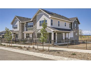 Charming townhome featuring stone accents, fenced yard, and modern architectural details at 95 N Vandriver Pl, Aurora, CO 80018