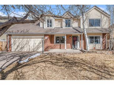 Charming two-story home featuring a brick facade, attached garage, and well-maintained front yard at 831 W Kettle Ave, Littleton, CO 80120