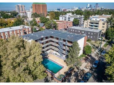 Apartment building featuring a swimming pool and an exterior staircase with city views and mature shade trees at 33 N Corona St # 205, Denver, CO 80218