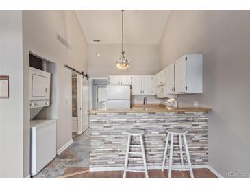 Cozy kitchen with white cabinetry, a breakfast bar with stone accent wall, and modern appliances at 7683 S Steele St, Centennial, CO 80122