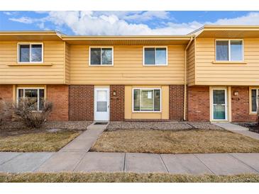 Tan brick front of a two-story townhouse with a small front yard at 12423 E Louisiana Ave, Aurora, CO 80012