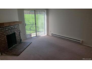 Spacious living room featuring a cozy brick fireplace and sliding glass doors to the outside at 14806 E 2Nd Ave Ave # 105G, Aurora, CO 80011
