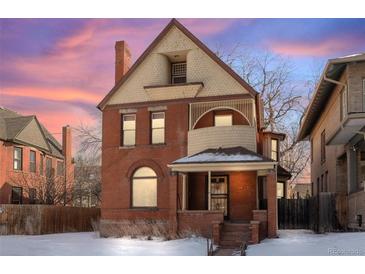 Brick two-story home with a wrap-around porch and snow-covered lawn at 1340 N Gilpin St, Denver, CO 80218